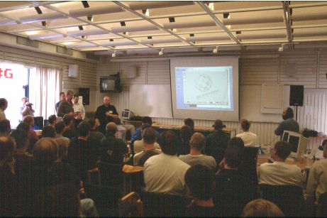 2: Just arrived at the event, a bit late after missing a ferry in Helsing&oslash;r and taking some wrong turns in Gothenburg. Ole-Egil Hvitmyren is answering questions after he and Justin Veggerby demonstrated their betatesting AmigaOne machines. Justin's machine is running UAE (with the files from his AmigaForever) on the big screen. Ole-Egil also ran UAE under Linux on his. To Ole-Egil's left you can see Kjell Breding (AmiGBG) in a blue shirt behind Gunne Steen (GGS-Data).
